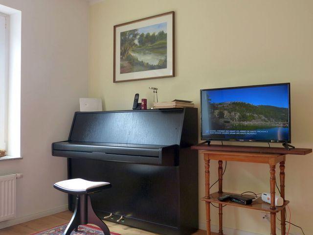 Wohnzimmer mit Klavier und TV